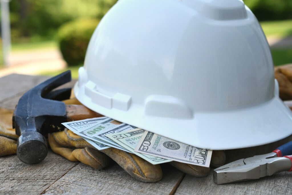 Hard hat with construction tools and cash money - concept for roofing cost or fraud, scam