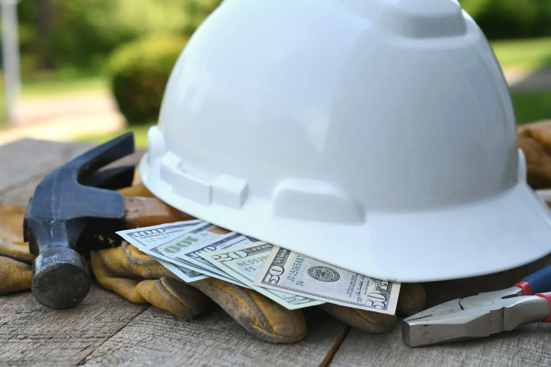 Hard hat with construction tools and cash money - concept for roofing cost or fraud, scam